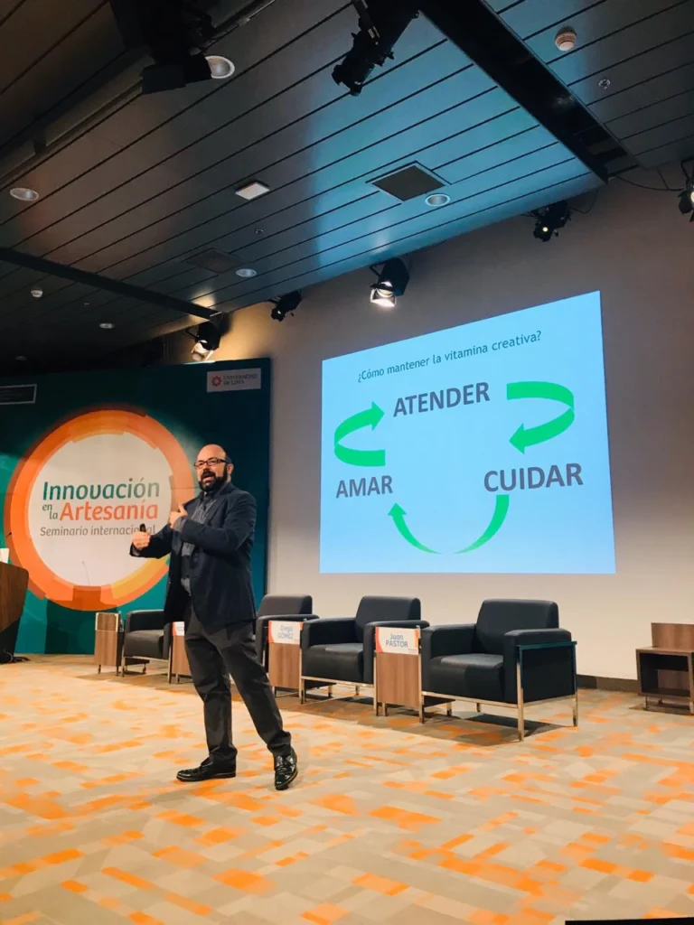 Juan Pastor Bustamante ofreciendo una conferencia sobre artesanía e innovación en un auditorio.