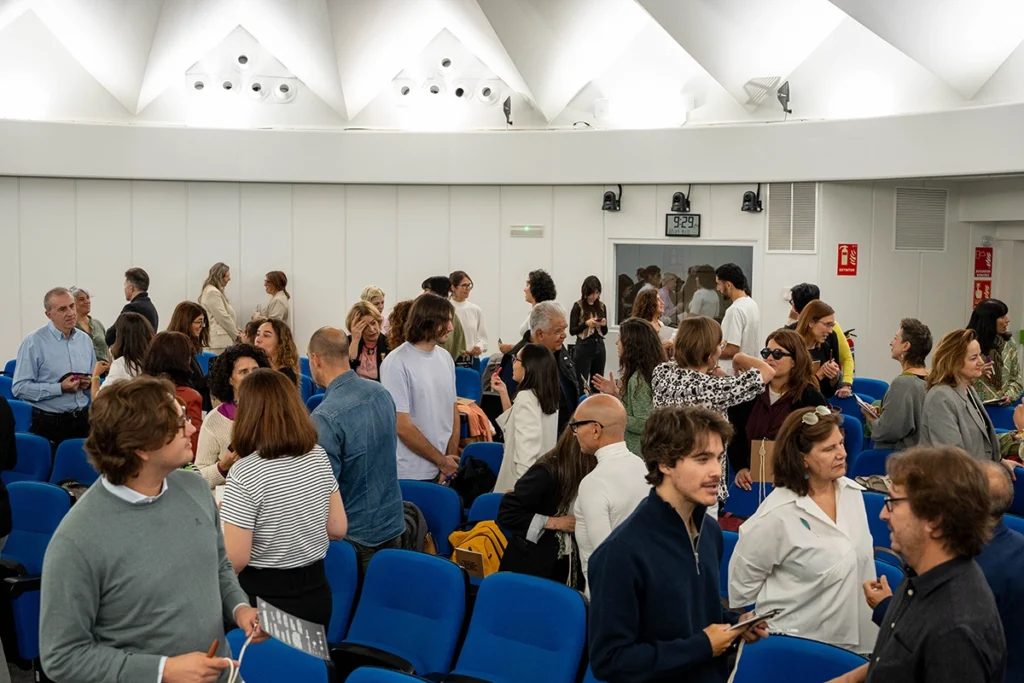 Asistentes conversando y haciendo networking tras un evento en un auditorio.